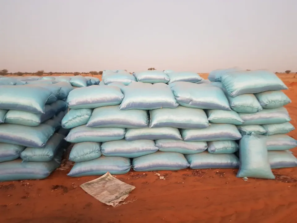 Sacks of harvested crop stacked on red soil, ready for collection
